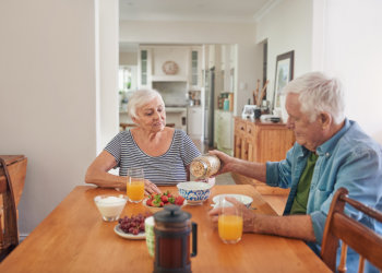 Smiling seniors enjoying a healthy breakfast at home together.