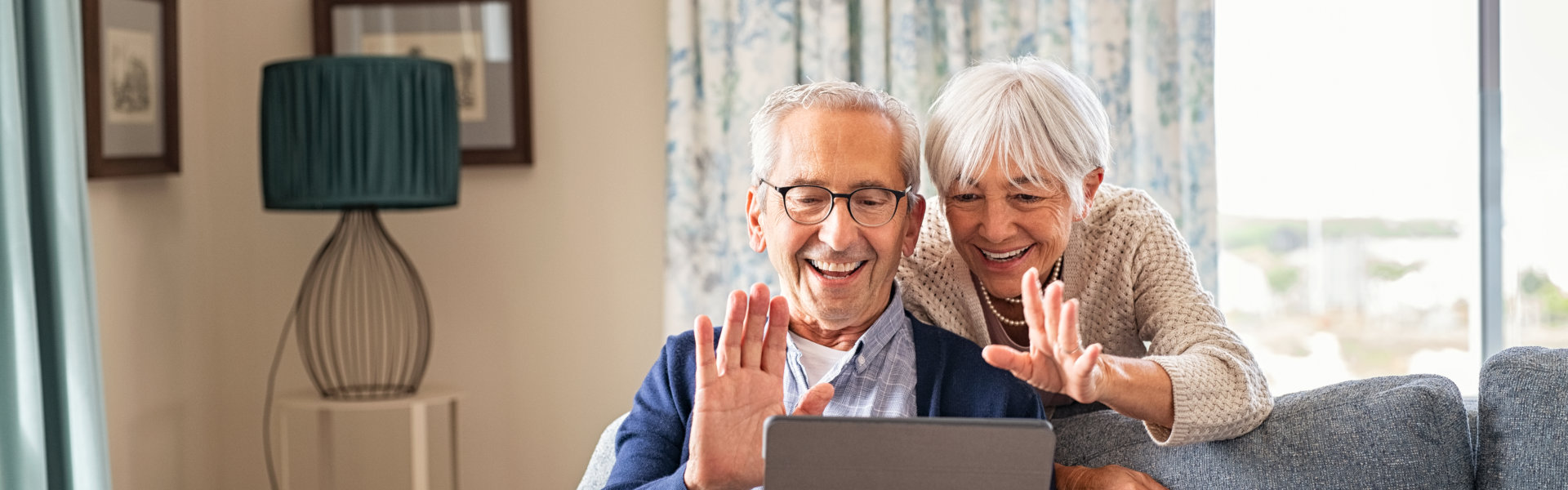 Elderly waving at someone in the laptop.