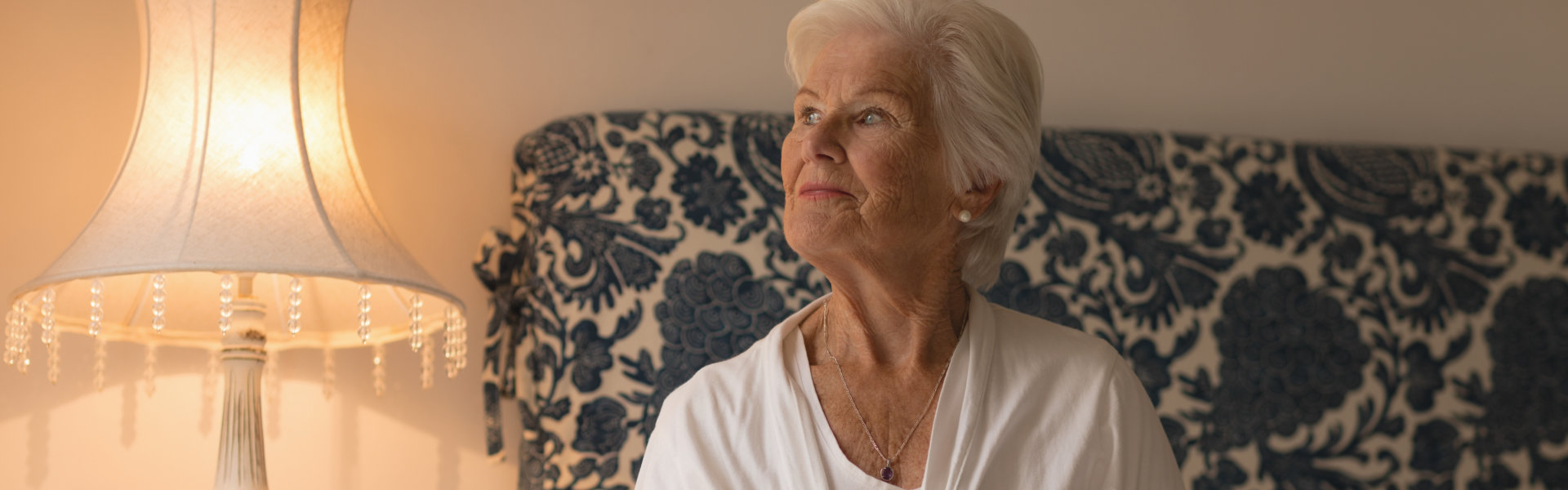 Senior woman sitting on her bed and relaxing in bedroom at home.